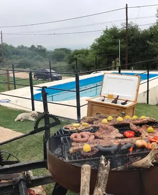 a grill with meat and vegetables on it next to a pool at Apart La Sole in Tanti