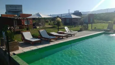 a swimming pool with two chairs and a table and an umbrella at La lomita de Nono in Arroyo de Los Patos