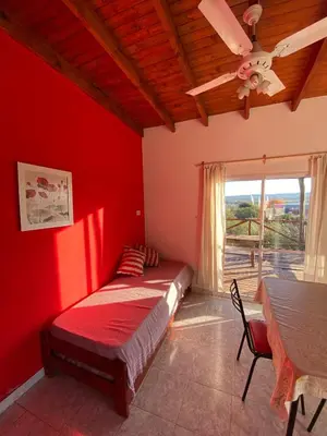 a bedroom with a red wall with a bed and a table at La lomita de Nono in Arroyo de Los Patos