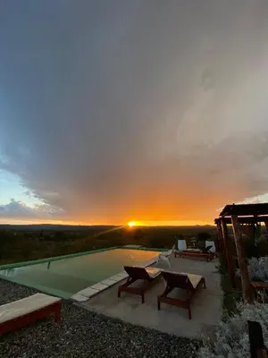 a swimming pool with a sunset in the background at La lomita de Nono in Arroyo de Los Patos
