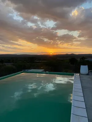 a swimming pool with a sunset in the background at La lomita de Nono in Arroyo de Los Patos