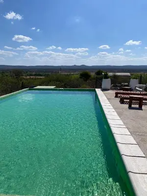 a swimming pool with green water and picnic tables at La lomita de Nono in Arroyo de Los Patos