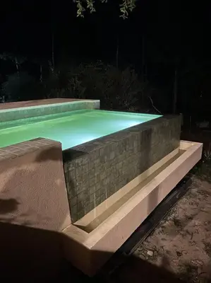a swimming pool at night with a stone wall at Casareartesesok in Los Reartes