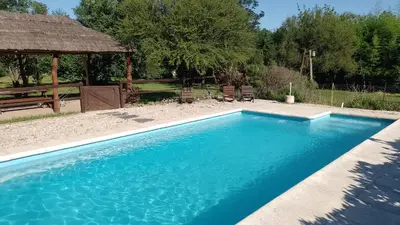 a swimming pool in a yard with a gazebo at La Brújula Hostel y Club Social in Mina Clavero