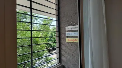 a cat is looking out of a window with a sign at Agradable departamento en Alta Córdoba in Cordoba