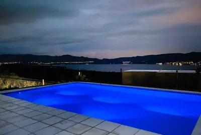 a blue swimming pool with a view of the water at Departamento Paris in Villa Carlos Paz