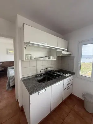 a kitchen with white cabinets and a sink and a window at Departamento Paris in Villa Carlos Paz