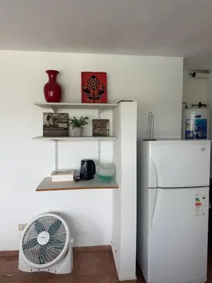 a kitchen with a white refrigerator and a fan at Departamento Paris in Villa Carlos Paz