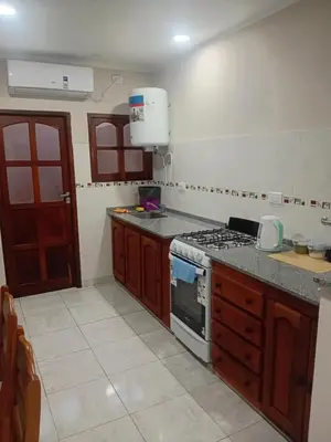 a kitchen with wooden cabinets and a stove top oven at Departamento calido, cerc in Río Tercero