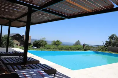 a swimming pool with chairs and a wooden pergola at Kentitaku cabañas de montaña in Las Rabonas