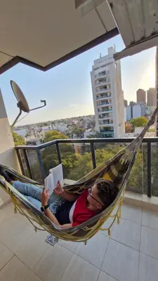 a man laying in a hammock reading a book at Bravo 6 - Luminoso y amplio depto cerca de todo! in Cordoba