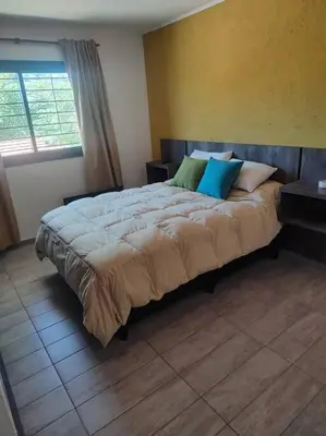 a bedroom with a large bed with pillows on it at Casa en las sierras de Córdoba con Deck , Parrilla y estacionamiento in Cavalango