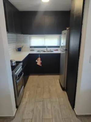 a small kitchen with a refrigerator and a stove at Casa en las sierras de Córdoba con Deck , Parrilla y estacionamiento in Cavalango