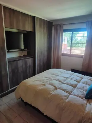a bedroom with a large bed and a television at Casa en las sierras de Córdoba con Deck , Parrilla y estacionamiento in Cavalango