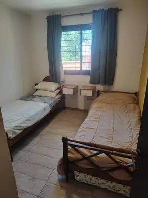 two beds in a small room with a window at Casa en las sierras de Córdoba con Deck , Parrilla y estacionamiento in Cavalango