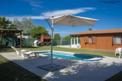 a pool with an umbrella and two chairs and a table at Potrero de Garay Los Espinillos in Potrero de Garay