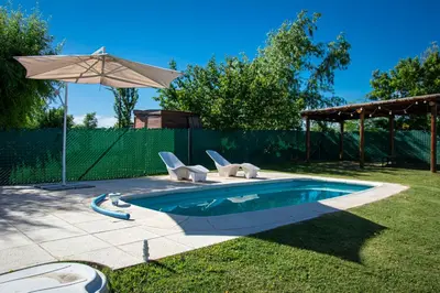 a swimming pool with two chairs and an umbrella at Potrero de Garay Los Espinillos in Potrero de Garay