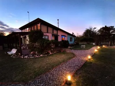 a house with lights in front of a yard at Loft Campestre - Los Reartes in Los Reartes