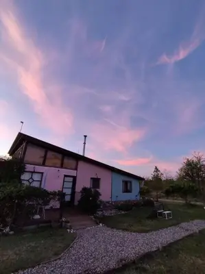 a white house with a cloudy sky behind it at Loft Campestre - Los Reartes in Los Reartes