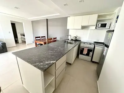 a kitchen with white cabinets and a black counter top at Departamento p 4 personas F Gral Paz in Cordoba