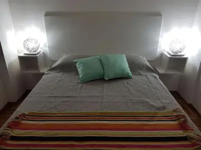 a bed with two green pillows in a bedroom at Achaval Nueva Córdoba Apartment in Cordoba
