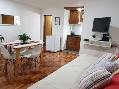 a room with a bed and a table and a kitchen at Achaval Nueva Córdoba Apartment in Cordoba