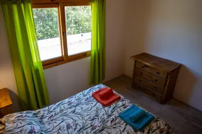 a bedroom with green curtains and a bed and a window at Cabañas Mi Respiro in Los Molles