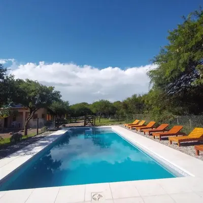 a swimming pool with chairs and blue water at Cabañas Mi Respiro in Los Molles