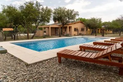 a swimming pool with benches next to a house at Cabañas Mi Respiro in Los Molles