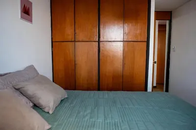 a bedroom with a bed and a wooden cabinet at El diez 1 dorm con COCHERA in Cordoba