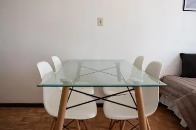 a glass table with white chairs and a couch at El diez 1 dorm con COCHERA in Cordoba