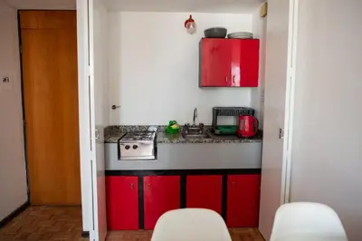 a small kitchen with red cabinets and a stove at El diez 1 dorm con COCHERA in Cordoba