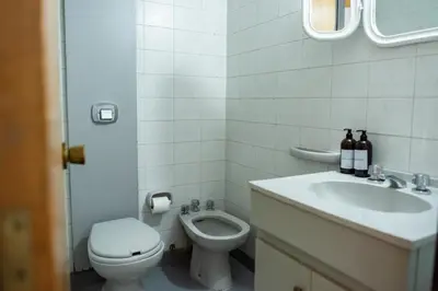 a white bathroom with a toilet and a sink at El diez 1 dorm con COCHERA in Cordoba