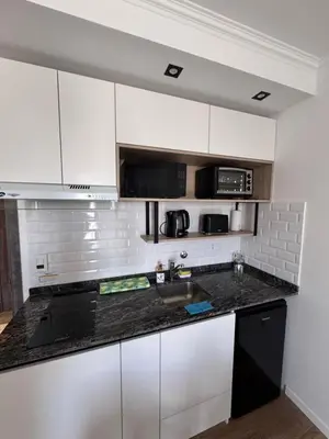 a kitchen with white cabinets and a black counter top at Carlos paz resort premium in Villa Carlos Paz