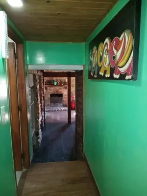 a hallway with a green wall and a fireplace at Refugio de las Sierras in Villa General Belgrano