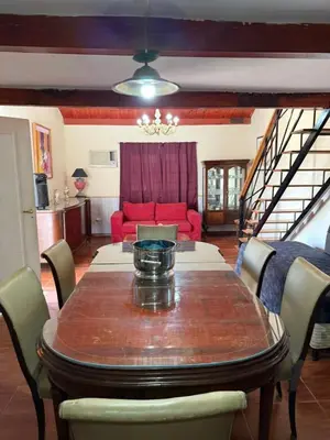 a dining room with a table and a red couch at Casa feliza in Villa Dolores