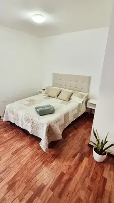 a bed in a white room with a wooden floor at Departamento en la Docta in Cordoba