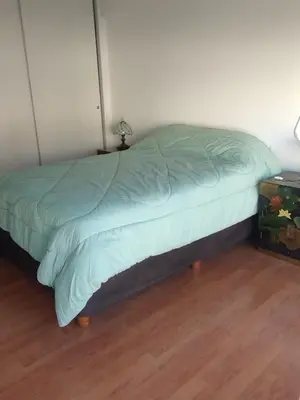 a bed with a green comforter in a room at Departamento con FERNET in Cordoba