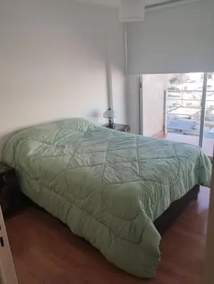 a bed with a green comforter in a bedroom at Departamento con FERNET in Cordoba