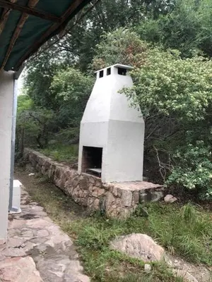 a small white building in the grass next to a house at Cabaña Tala Huasi in Villa Icho Cruz