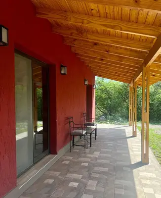 a patio with chairs and a red building at Refugio Serrano in Merlo