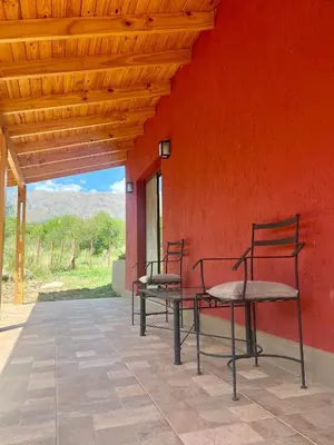 two chairs sitting on the side of a red wall at Refugio Serrano in Merlo