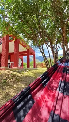 a hammock in front of a house with trees at Refugio Serrano in Merlo