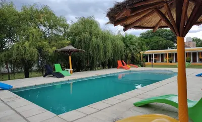 a swimming pool with colorful chairs and an umbrella at BALCON De LA SIERRA in Las Calles