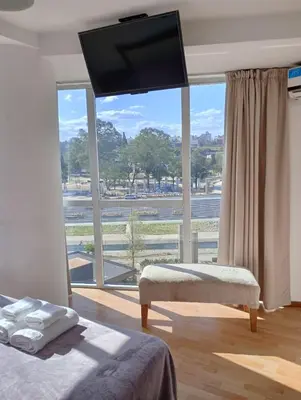 a bedroom with a large window with a flat screen tv at Departamento Polanco Tower in Cordoba