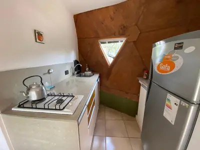 a small kitchen with a stove and a refrigerator at Domos in Santa Rosa de Calamuchita