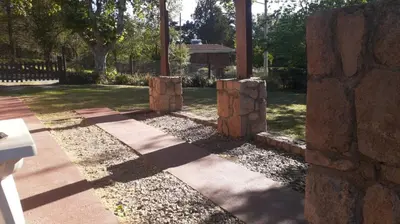 a stone wall with three logs in a yard at La Casa de la Esquina in Villa Icho Cruz