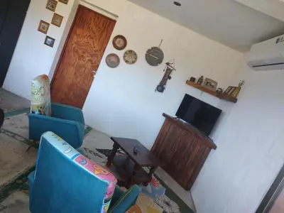 a living room with a blue chair and a television at La Casita de Villa Yacanto in Villa Yacanto