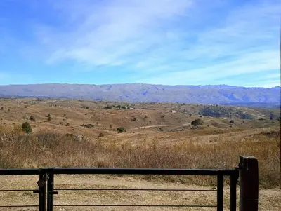 a fence in a field with mountains in the background at La Casita de Villa Yacanto in Villa Yacanto