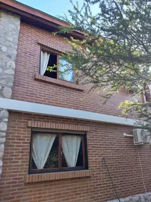 a brick house with two windows with white curtains at soy ahora 1 y 2 in Pueblito